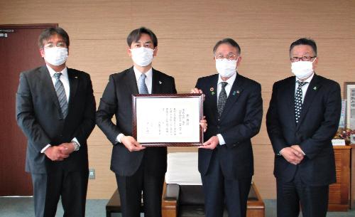 感謝状を掲げる臂市長と株式会社三共の高井常務執行役員
