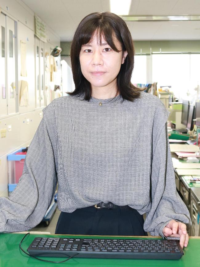 窓口に立ちパソコンを操作する建設部道路維持課岡庭美咲写真