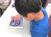 タブレットでプログラミングをして、水族館の絵を描いたり、簡単なゲームをしている子供の写真