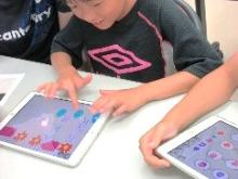 子供がタブレットでで、プログラミングをしてゲームをしている写真