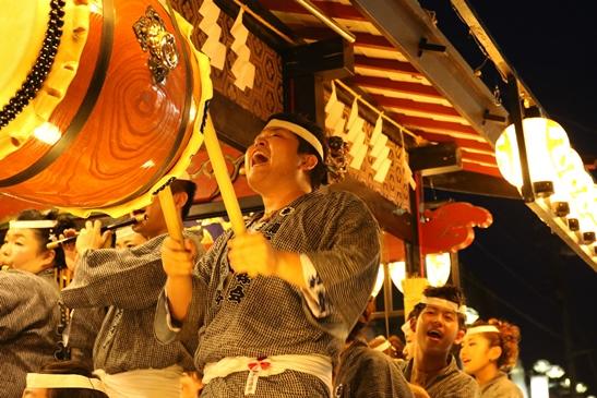 夏祭りで山車の上で男性が太鼓を叩いている写真です