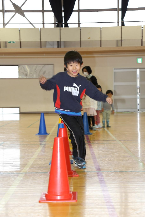 子どもがコーンの間を楽しそうに駆ける写真