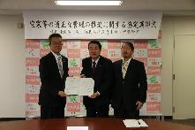 災害対策室で群馬行政書士会2人と五十嵐市長が協定書を携えている写真