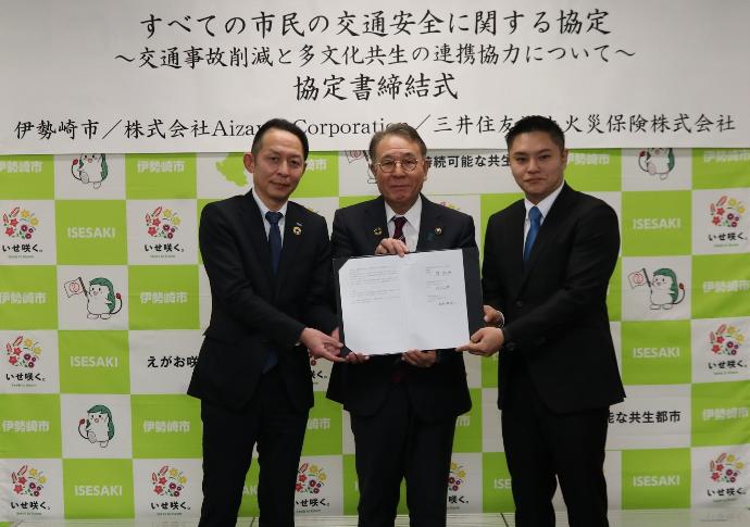 すべての市民の交通安全に関する協定締結式。三井住友海上火災保険株式会社の代表、伊勢崎市長、アイザワコーポレーションの代表が並んで記念写真。