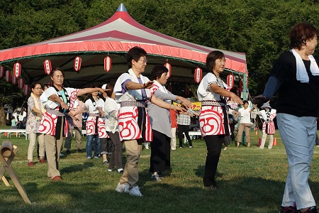 芝生の上で法被を着た参加者が民踊を踊っている様子