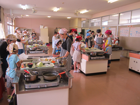 親子料理教室の写真です。調理室で20人ほどの親子が料理しています
