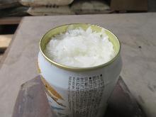 まいぎり式の火おこしで作った火で、アルミ缶を使ってご飯を炊いた写真