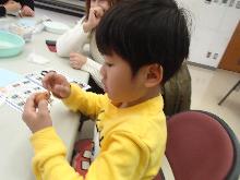 まゆにのイノシシのパーツを付けて、昨年の干支を作っている子供の写真