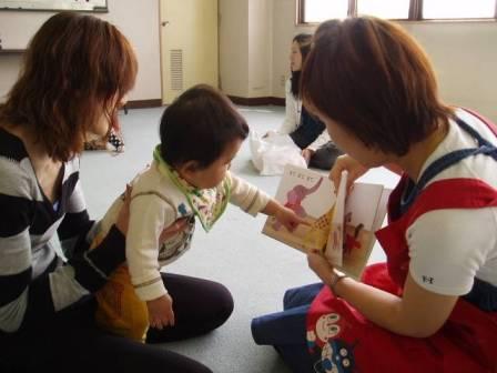 ボランティアが赤ちゃんとお母さんに絵本を読んで聞かせている写真